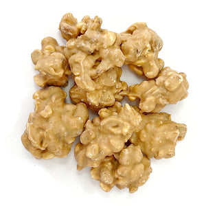 A cluster of Chocolate Caramel Peanuts Cluster pieces with sea salt on a white background.