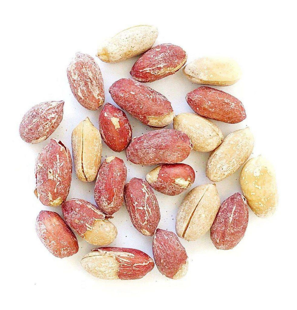 A handful of roasted salted peanuts, famous for their potential in savory dishes, are scattered against a white background.