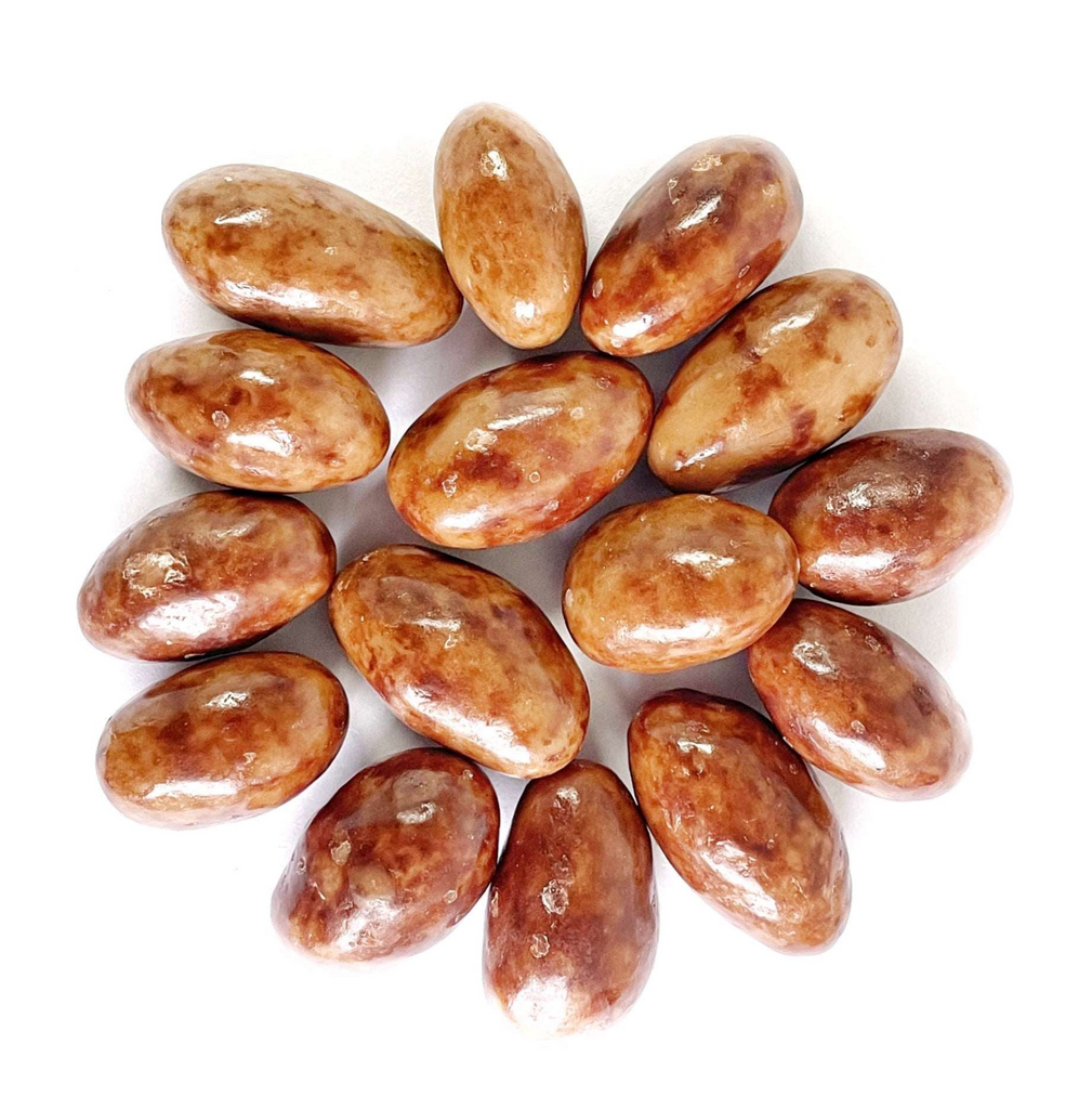 Fifteen oval, marbled brown White Chocolate Caramel Almonds are arranged in a neat, circular pattern on a white background.