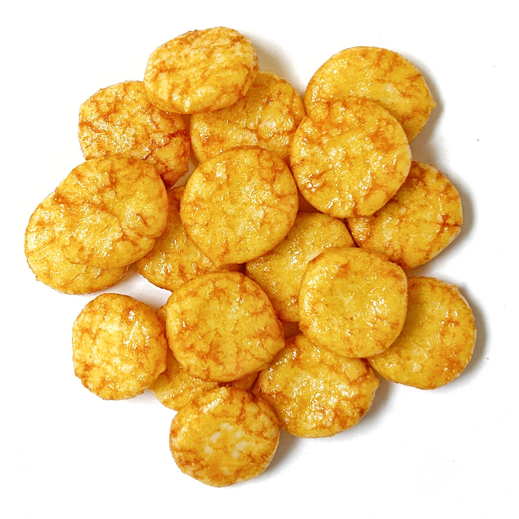 A stack of Baked Chilli Rice Crackers, with their round, golden-brown appearance on a white background, suggests a spicy flavor in every bite.